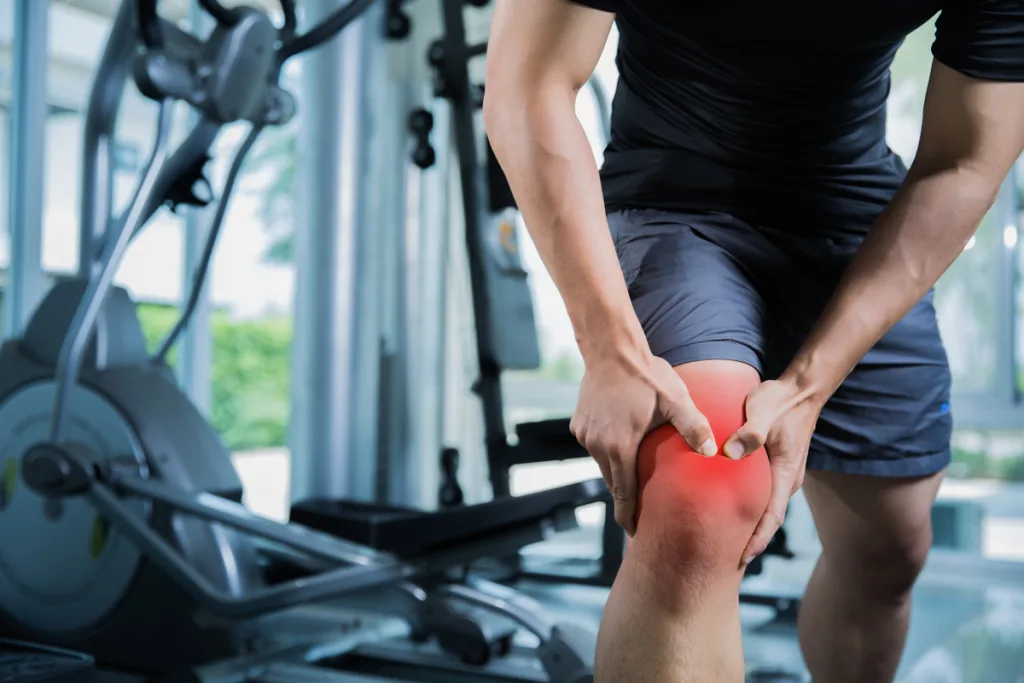 man experiencing knee pain in gym